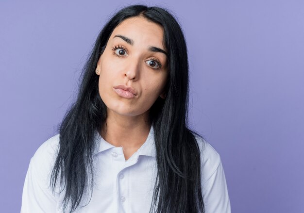 Het droevige jonge donkerbruine Kaukasische meisje kijkt geïsoleerd op purpere muur
