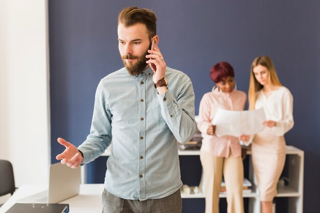 Het ernstige mens seaking op telefoon dichtbij collega&#39;s