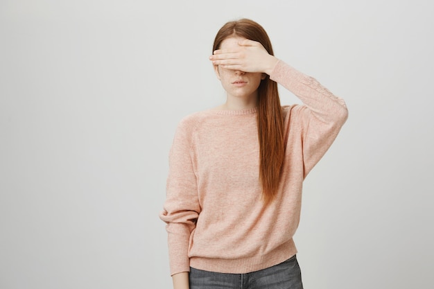 Het ernstige roodharige meisje behandelt haar ogen met hand