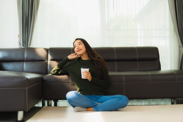 Het gebruik slimme mobiele telefoon van de portret mooie jonge Aziatische vrouw met koffiekop