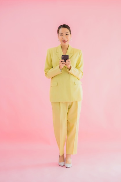 Het gebruik van portret mooie jonge Aziatische bedrijfsvrouw slimme mobiele telefoon met koffiekop op kleur