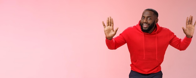 Het gelukkige charmante uitgaande afro-amerikaanse mannelijke model steekt handen op een grapje staande overgave lachende gi