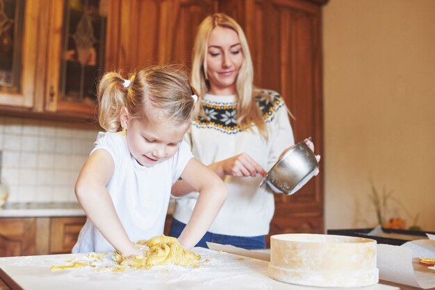 Het gelukkige glimlachende mamma in de keuken bakt koekjes met haar dochter.