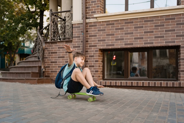 Het gelukkige jonge jongen spelen op skateboard in de stad, Kaukasisch jong geitje die stuiverraad berijden