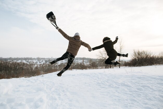 Het gelukkige jonge paar in liefde springt van vreugde. Koude sneeuw winterdag. Winter liefdesverhaal.