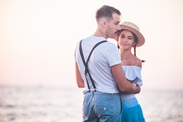 Het gelukkige jonge romantische paar ontspannen op het strand en het letten op de zonsondergang