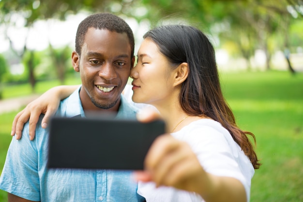 Het gelukkige knappe jonge Afrikaanse kerel stellen voor selfie terwijl zijn Aziatisch meisje