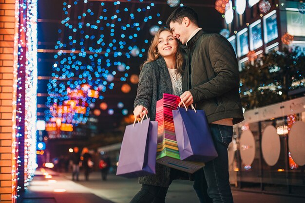 Het gelukkige paar met boodschappentassen genieten van de nacht in de stad