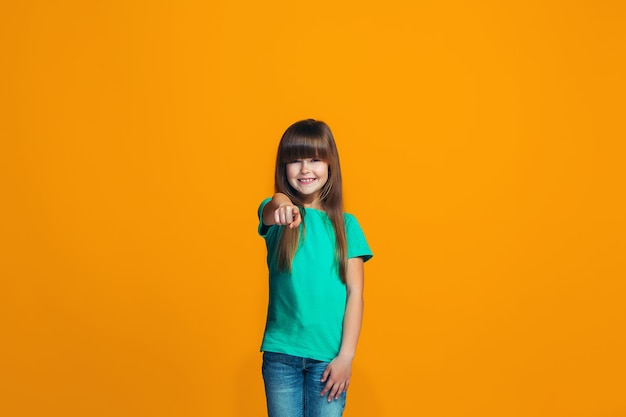 Het gelukkige tienermeisje dat aan u, het halve portret van de lengteclose-up op oranje ruimte richt.