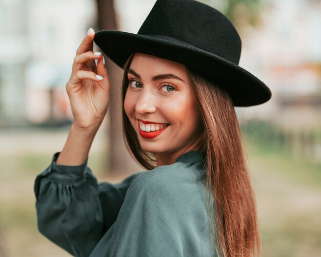 Het gelukkige vrouw stellen met een zwarte hoed