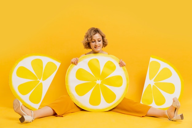 Gratis foto het gelukkige vrouw stellen met het decor van citroenplakken