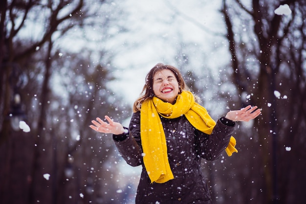 Gratis foto het gelukkigste meisje dat met sneeuw in het park speelt