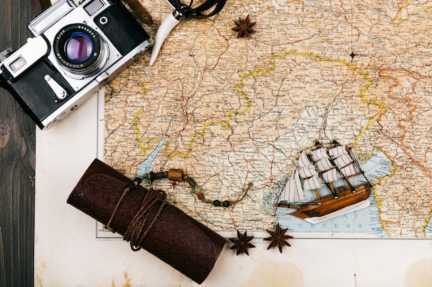 Het geval en de camera van het leer liggen op de toeristische kaart met klein houten schip