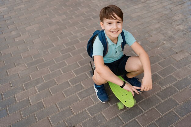 Het glimlachen het jonge jongen spelen op skateboard in de stad, Kaukasisch jong geitje die stuiverraad berijden