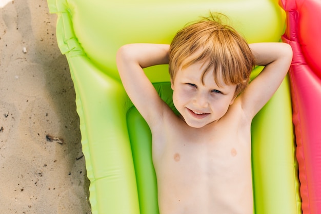 Het glimlachen jongen het ontspannen op luchtmatras op strand in de zomervakantie