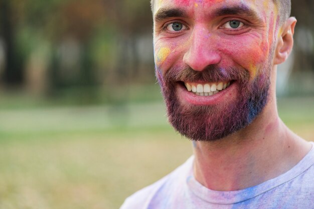 Het glimlachen mens het stellen met geschilderd gezicht bij holi