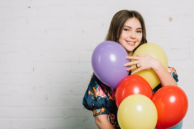 Het glimlachen portret van de ballons van een tienerholding