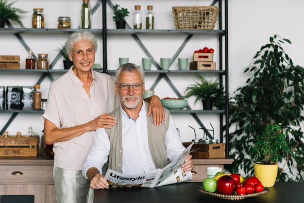 Het glimlachen portret van een bejaardezitting in de keuken