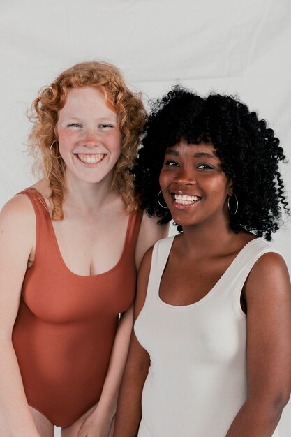 Het glimlachen portret van jonge diverse vrouwen die aan camera tegen grijze achtergrond kijken