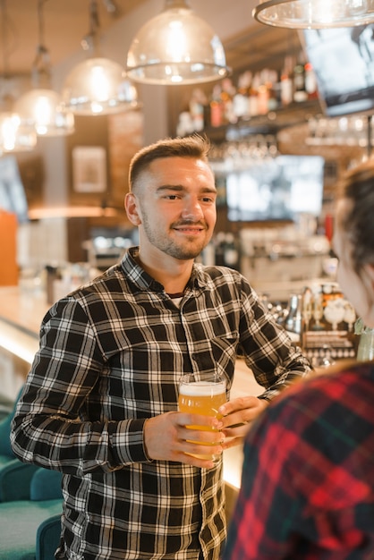 Het glimlachen van het glas van de jonge mensenholding bier met haar vriend