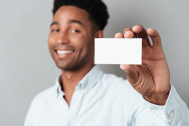 Het glimlachen van jonge afro Amerikaanse kerel die leeg adreskaartje toont