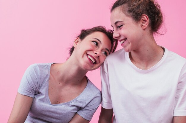 Het glimlachen van vrouwen leunend hoofd op de schouder van haar vriend over roze achtergrond