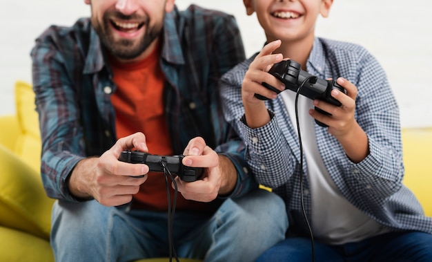 Het glimlachende vader en zoon spelen op console