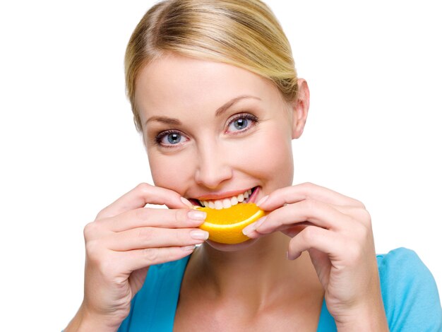 Het glimlachende volwassen meisje eet het plakje van een verse sinaasappel