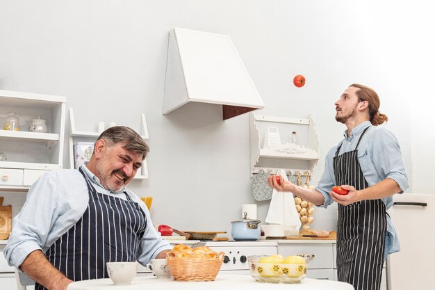 Het grappige zoon jongleren met met tomaten