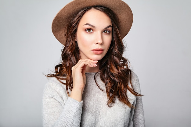 Het horizontale portret van stijlvol aantrekkelijk vrouwelijk model draagt zomerkleren en bruine hoed met natuurlijke make-up