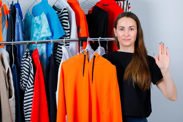 Het houden van sweetshirt girl toont hallo gebaar op kledingachtergrond