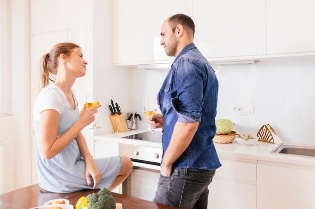 Het houden van van het wijnglas die van de paarholding eachother in keuken bekijken