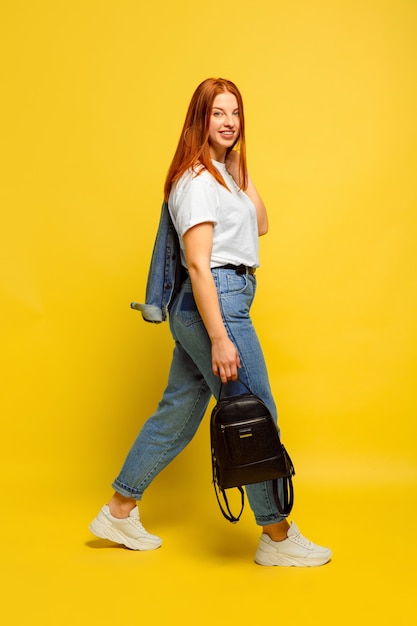 Het is gemakkelijker om een volgeling te zijn. Minimale kleding nodig om te gaan. Kaukasische vrouw portret op gele achtergrond. Mooi vrouwelijk rood haarmodel. Concept van menselijke emoties, gezichtsuitdrukking, verkoop, advertentie.