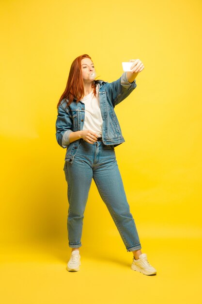 Het is gemakkelijker om een volgeling te zijn. Minimale kleding nodig voor selfie. Kaukasische vrouw portret op gele achtergrond. Mooi vrouwelijk rood haarmodel. Concept van menselijke emoties, gezichtsuitdrukking, verkoop, advertentie.