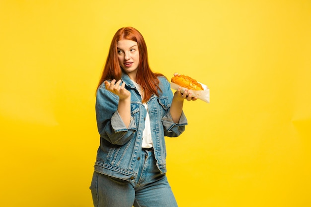 Het is gemakkelijker om een volgeling te zijn. U hoeft geen foto te maken met eten. Blanke vrouw op gele achtergrond. Mooi vrouwelijk rood haarmodel. Concept van menselijke emoties, gezichtsuitdrukking, verkoop, advertentie.