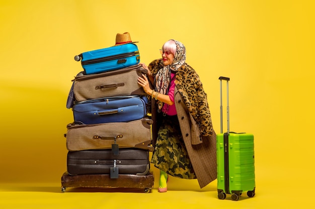 Het is moeilijk om influencer te zijn. Veel kleding om op reis te gaan. Kaukasische vrouw portret op gele achtergrond. Mooi blond model. Concept van menselijke emoties, gezichtsuitdrukking, verkoop, advertentie.
