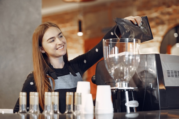 Het jonge baristameisje maakt koffie en glimlacht