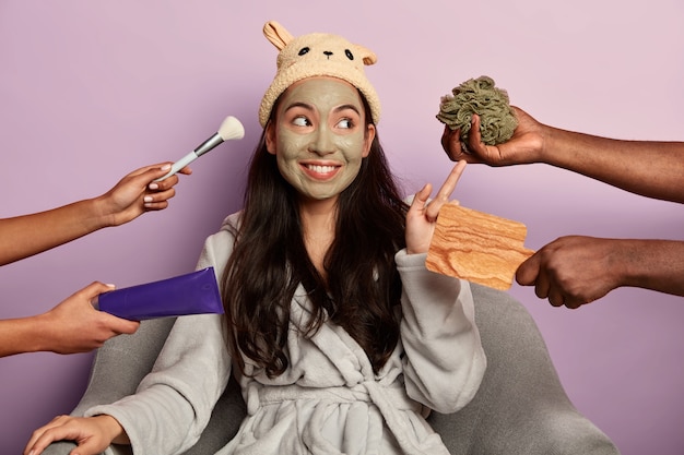 Het jonge duizendjarige meisje past een organisch gezichtsmasker toe op het gezicht na het nemen van een douche