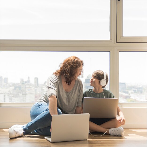 Het jonge jongen spelen op laptop naast mamma