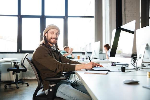 Gratis foto het jonge knappe mensenwerk in bureau dat computer met behulp van