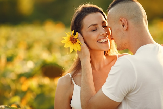 Het jonge liefdevolle paar kust in een zonnebloemgebied. Portret van paar poseren in de zomer in veld.