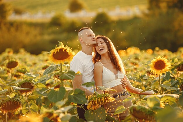 Het jonge liefdevolle paar kust in een zonnebloemgebied. Portret van paar poseren in de zomer in veld.