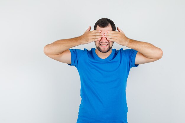 Het jonge mannetje dat ogen behandelt dient blauw t-shirt in en kijkt vrolijk