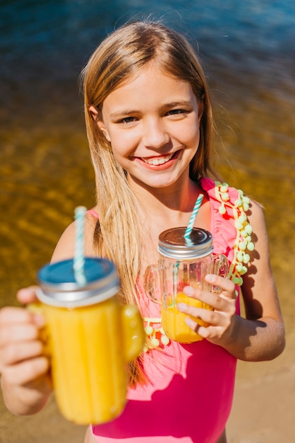 Het jonge meisje biedt drank aan terwijl status op strand