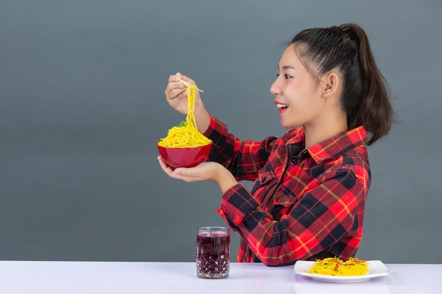 Het jonge meisje geniet thuis van etend spaghetti