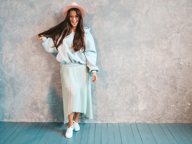 Het jonge mooie glimlachende vrouw kijken. Trendy meisje in casual zomer hoodie en rok kleding.