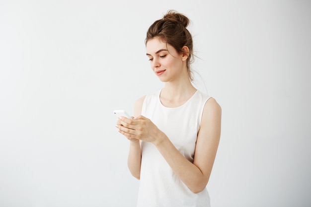 Het jonge mooie vrouw glimlachen die telefoon bekijkt