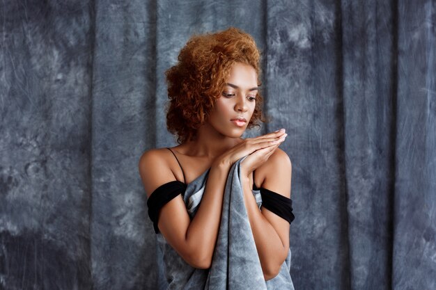 Het jonge mooie vrouw stellen, die zich in grijze doek verpakken