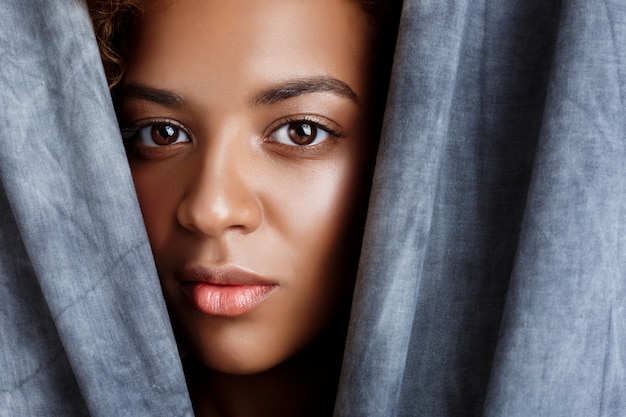 Gratis foto het jonge mooie vrouw stellen, die zich in grijze doek verpakken