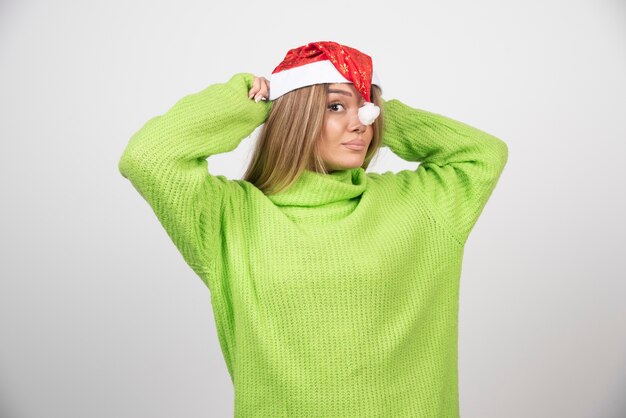 Het jonge mooie vrouw stellen in de rode hoed van de Kerstman
